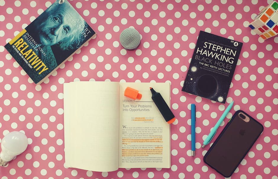 Flat lay of books, stationery, and gadgets on a polka dot desk for a vibrant study setup.