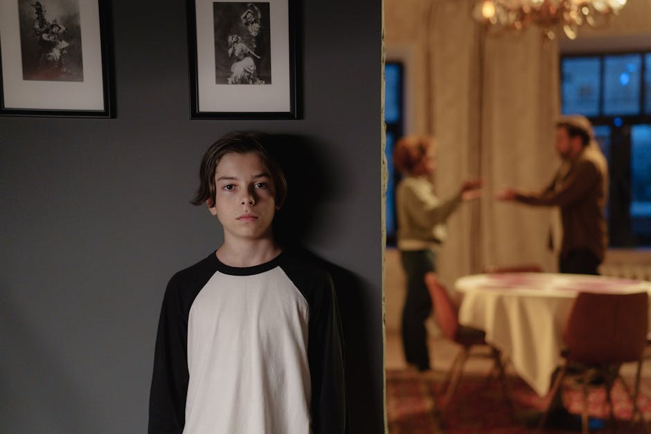 A boy stands in focus, while two adults argue in the background, depicting family conflict.