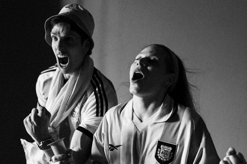 Excited sports fans cheer passionately, capturing the thrill of the game in a black and white photo.