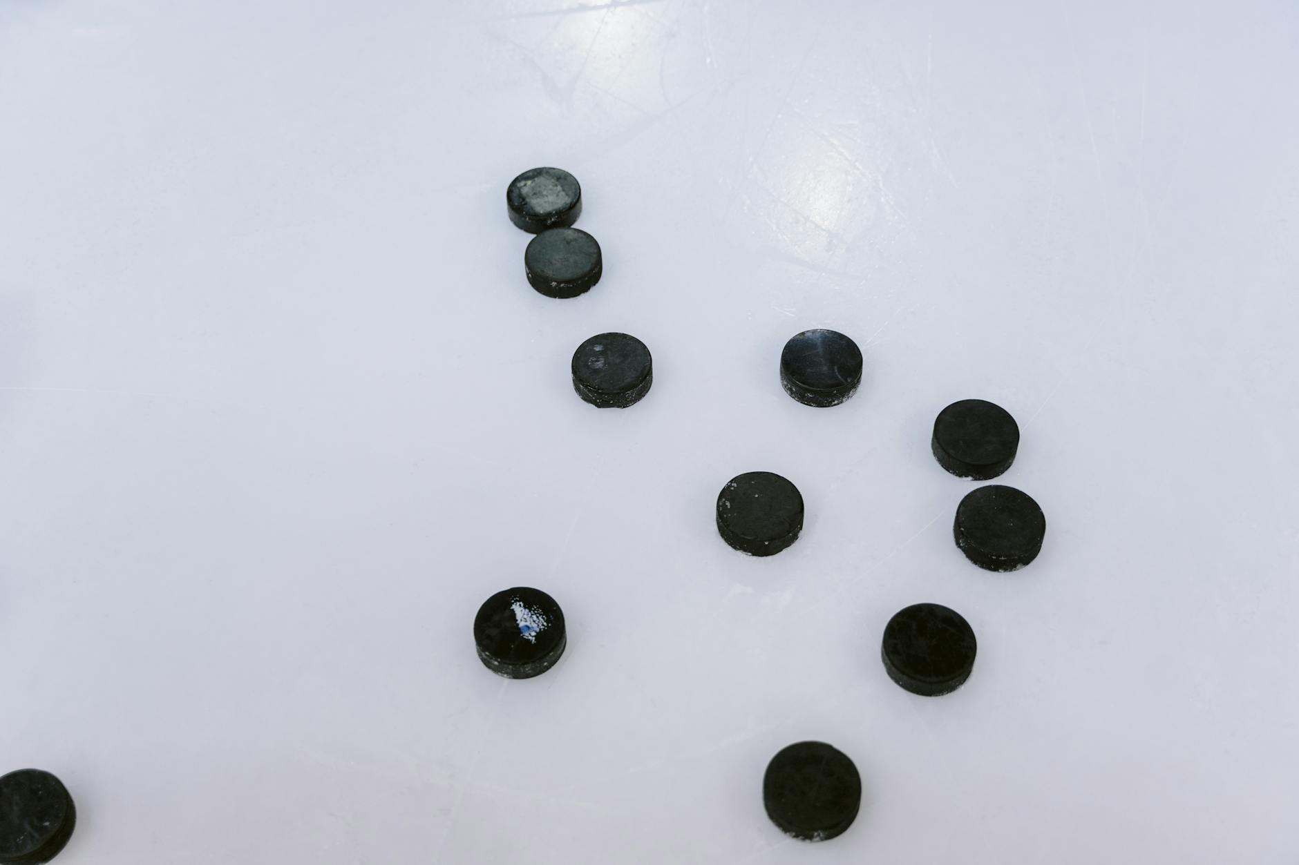 Multiple ice hockey pucks scattered on a smooth, frozen surface.