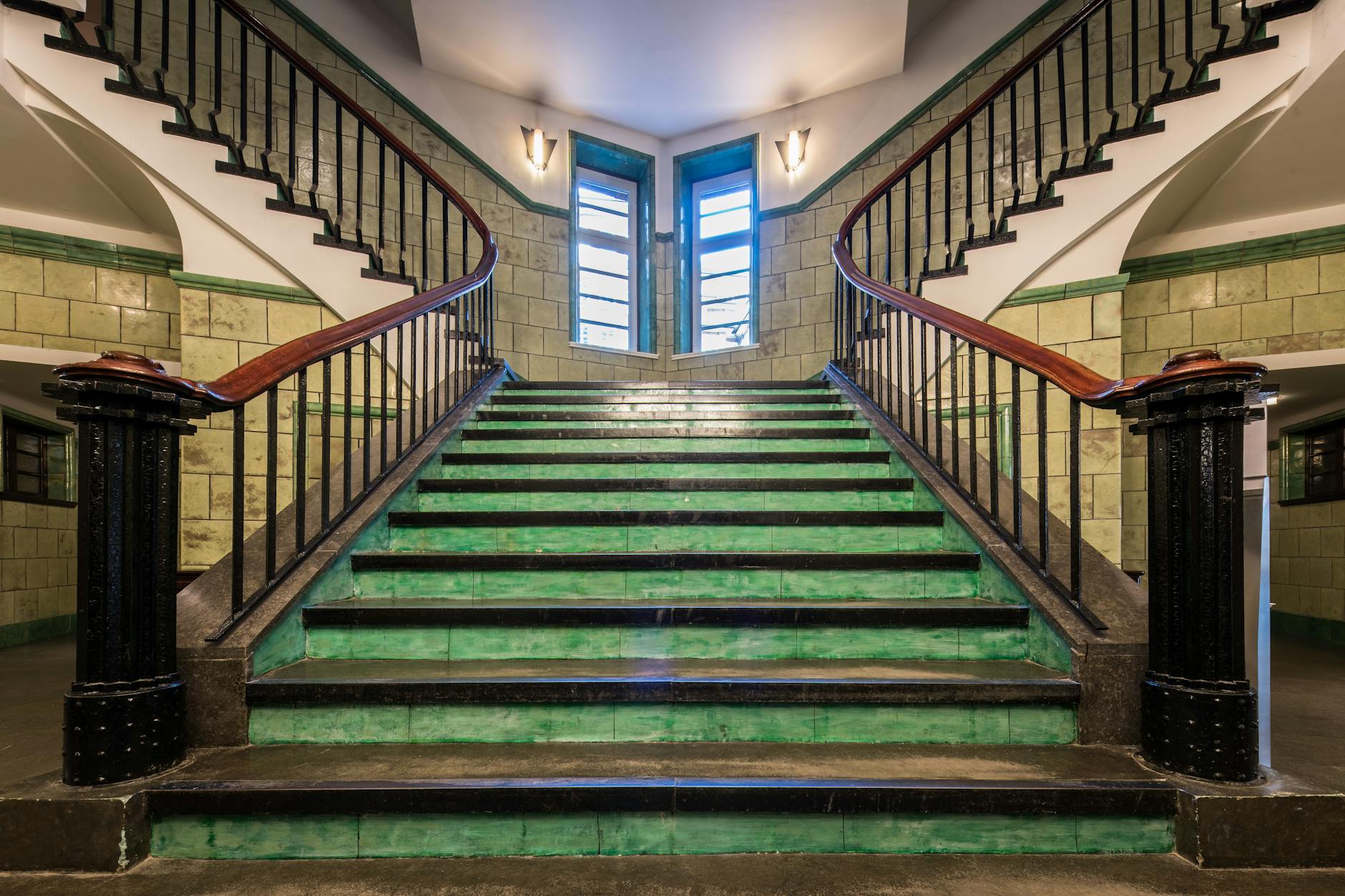Historic stairwell with green tiles and iron railings in Hamburg, Germany.