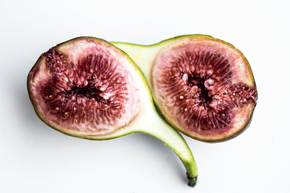 Detailed close-up of a sliced fig showcasing its vibrant interior on a white background.