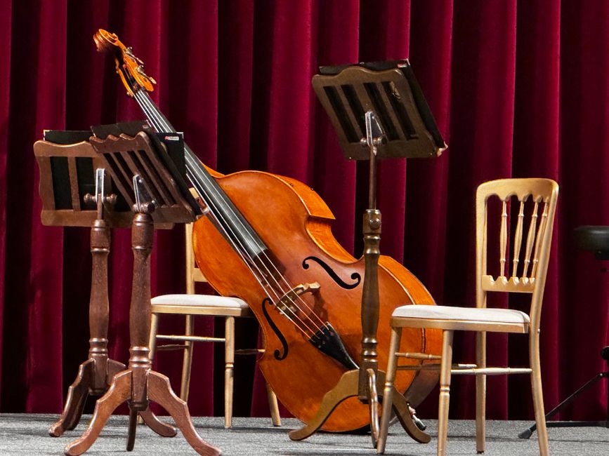 An empty stage with a cello and music stands ready for a classical concert.